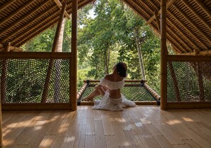 A room with a wooden floor, a bamboo ceiling, and a view of greenery outside. - Kayun Sidemen (Sidemen)