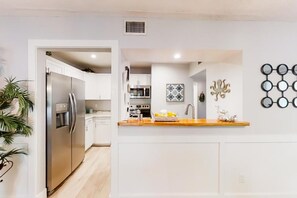 Eine moderne Küche mit weißen Schränken, Edelstahlgeräten und einer Holz Arbeitsplatte.