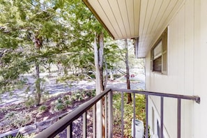 Ein Wohnhaus mit überdachter Veranda, einer Treppe zum Eingang und Blick auf die Straße sowie die umliegenden Bäume.