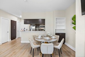 A modern kitchen with dark cabinetry, a central island, and a dining area with a round table and chairs. - Cozy 2-bedroom apartment with AC in welcoming Dallas (Dallas)