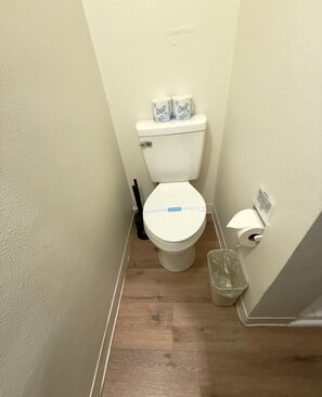 Ein kleines Badezimmer mit Toilette, Toilettenpapier und einem Mülleimer.