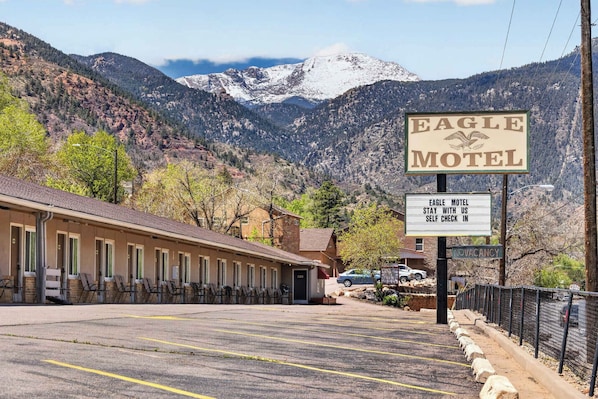 Ein Motel vor einer Bergkulisse, mit Schild für Selbstcheck-in und einem Hinweis auf freie Zimmer.