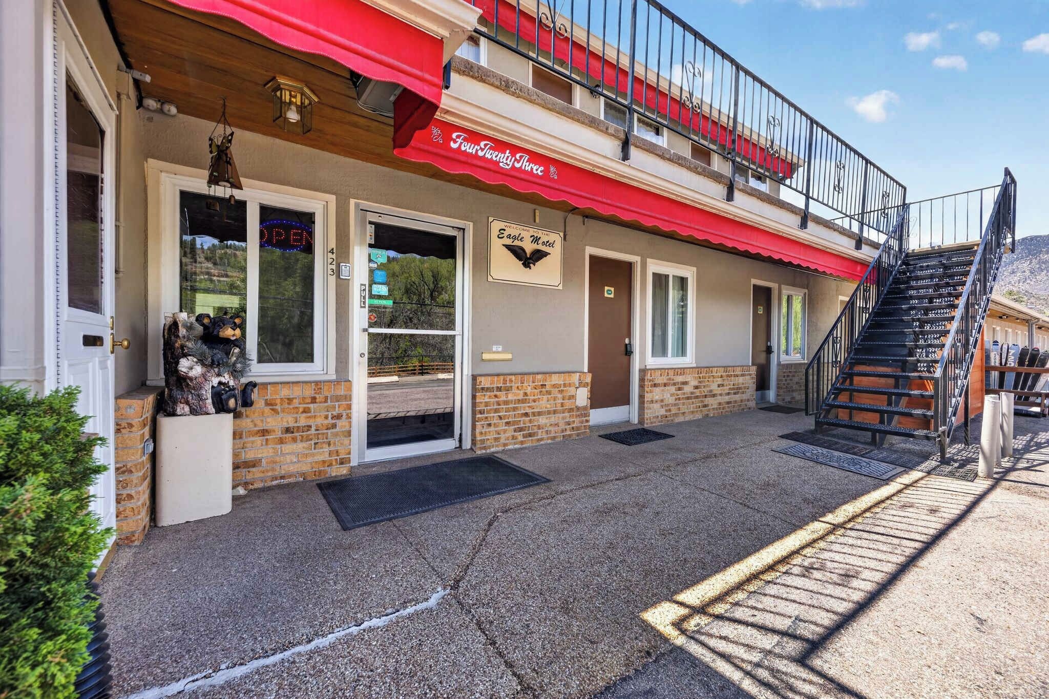 A hotel with a red awning, a staircase, and a sign for the Eagle Motel.