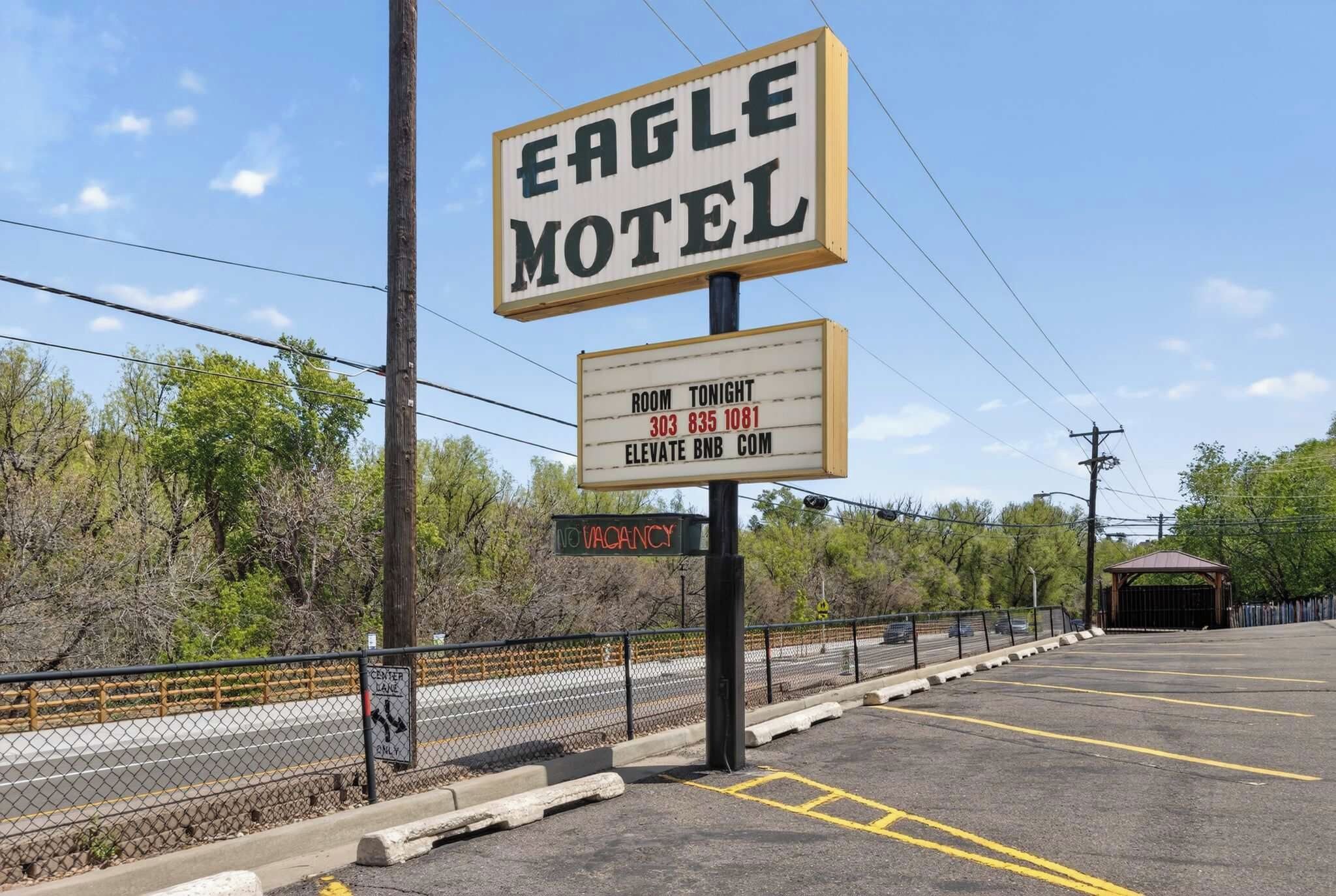 Une enseigne de motel, une pancarte indiquant qu’il y a des chambres disponibles et un parking délimité par une clôture.