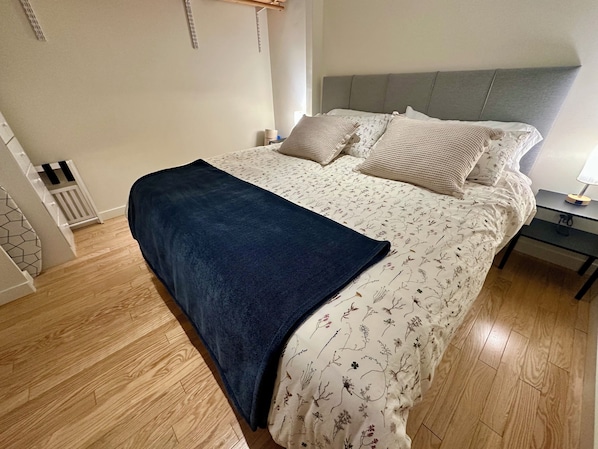A bedroom with a bed, a bedside table, and a nightstand.