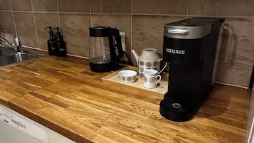 Een keuken met een houten aanrecht, een koffiezetapparaat, een waterkoker en een spoelbak.