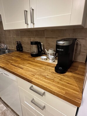 A kitchen with a wooden countertop, a coffee maker, a kettle, and a sink.