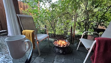 Eine Terrasse mit Feuerstelle, zwei Stühlen und einem Tisch mit einer Tasse.