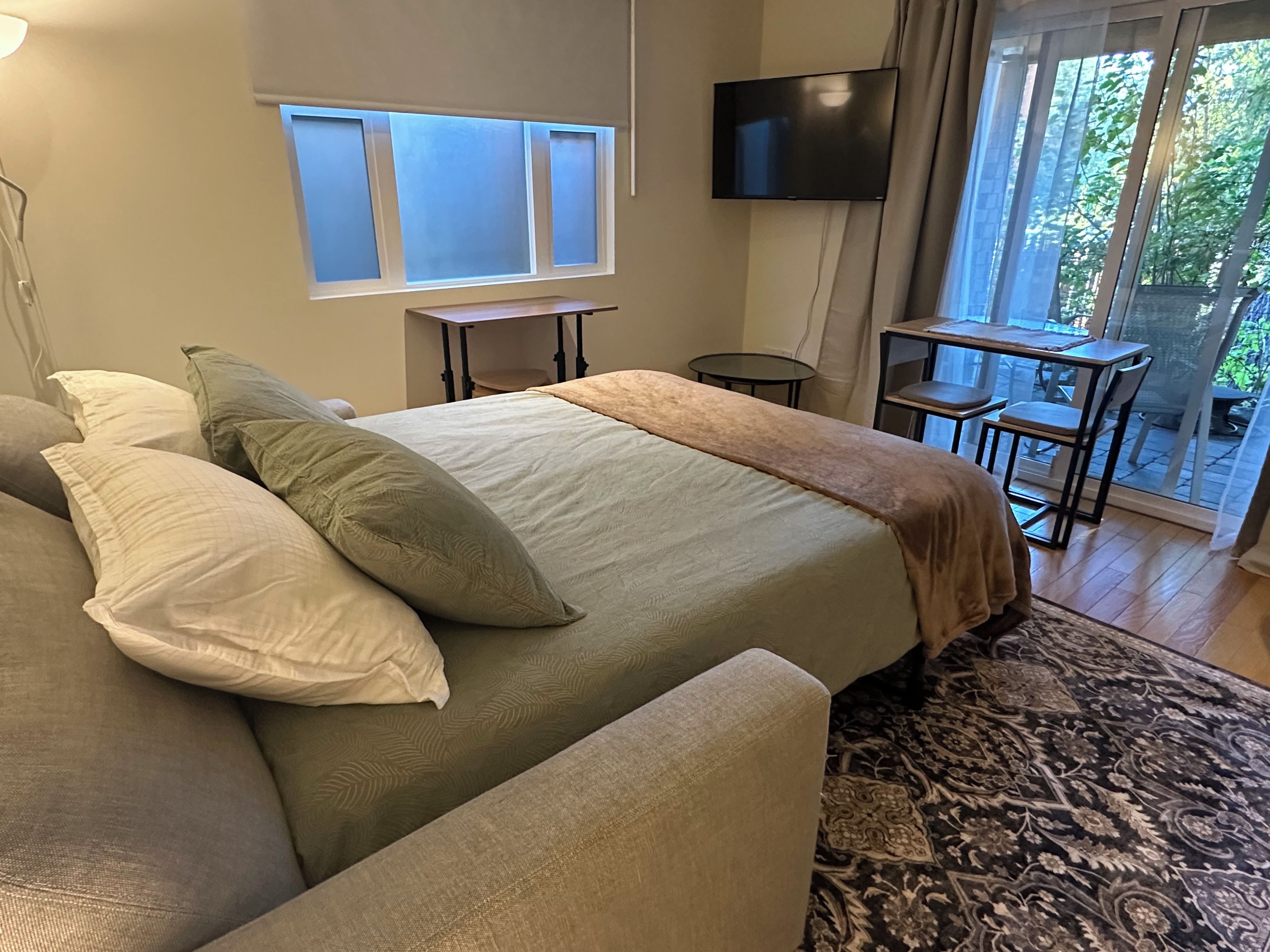 Une chambre avec un lit, une télévision, une petite table et une vue sur l’extérieur.