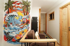 A room with a colorful mural, a brown sofa, a small table, and a wooden door.