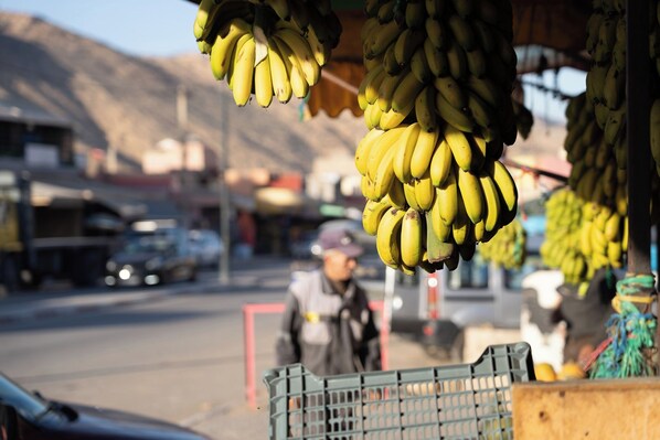 A street scene with a fruit stand displaying bananas.