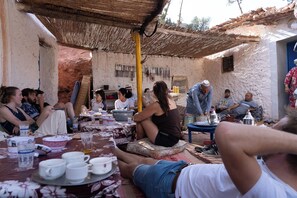 A group of people seated at tables outdoors, engaged in conversation and dining.