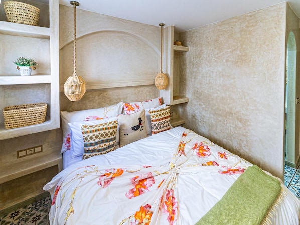 Un dormitorio con cama, estanterías y luces colgantes.