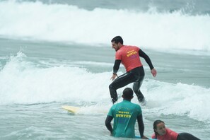 Un surfista con traje de neopreno montando una ola.
