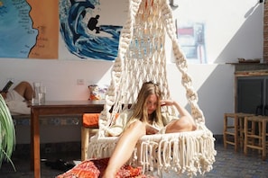 A room with a macrame chair, a map on the wall, and a tiled floor. - Waves Hunter Surf House - Anza (Agadir)
