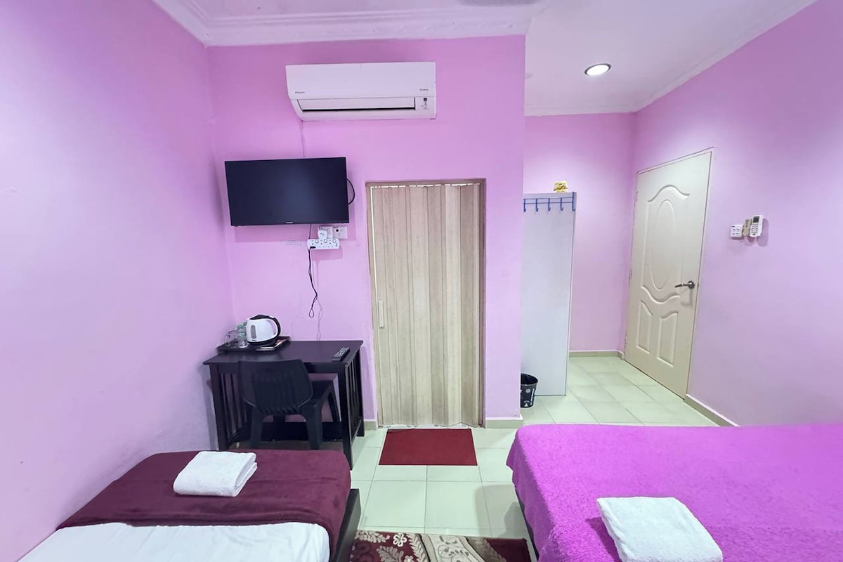Una habitación con dos camas, un escritorio con televisor, aire acondicionado y una puerta.