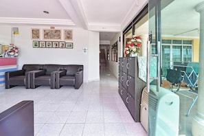 A hotel lobby with a reception desk, a sofa, and a wall with framed pictures.