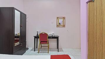 Una habitación con cama, un armario, un escritorio con silla y un espejo en la pared.