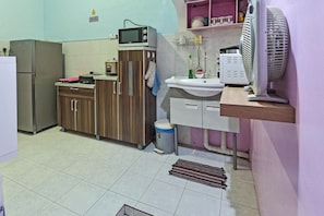 A compact kitchen with a refrigerator, microwave, sink, and a fan. - Darul Salam Orkid INN By Zuzu (Kerteh)