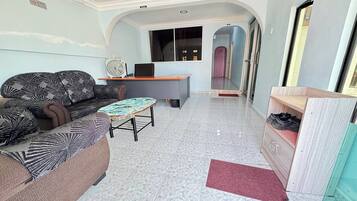 A living room with a sofa, a small round table, and a desk with a computer.