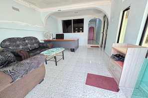 A living room with a sofa, a small round table, and a desk with a computer. - Darul Salam Orkid INN By Zuzu (Kerteh)