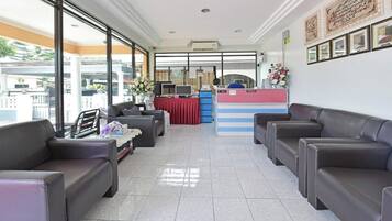 A hotel reception area with leather seating, a reception desk, and large windows.