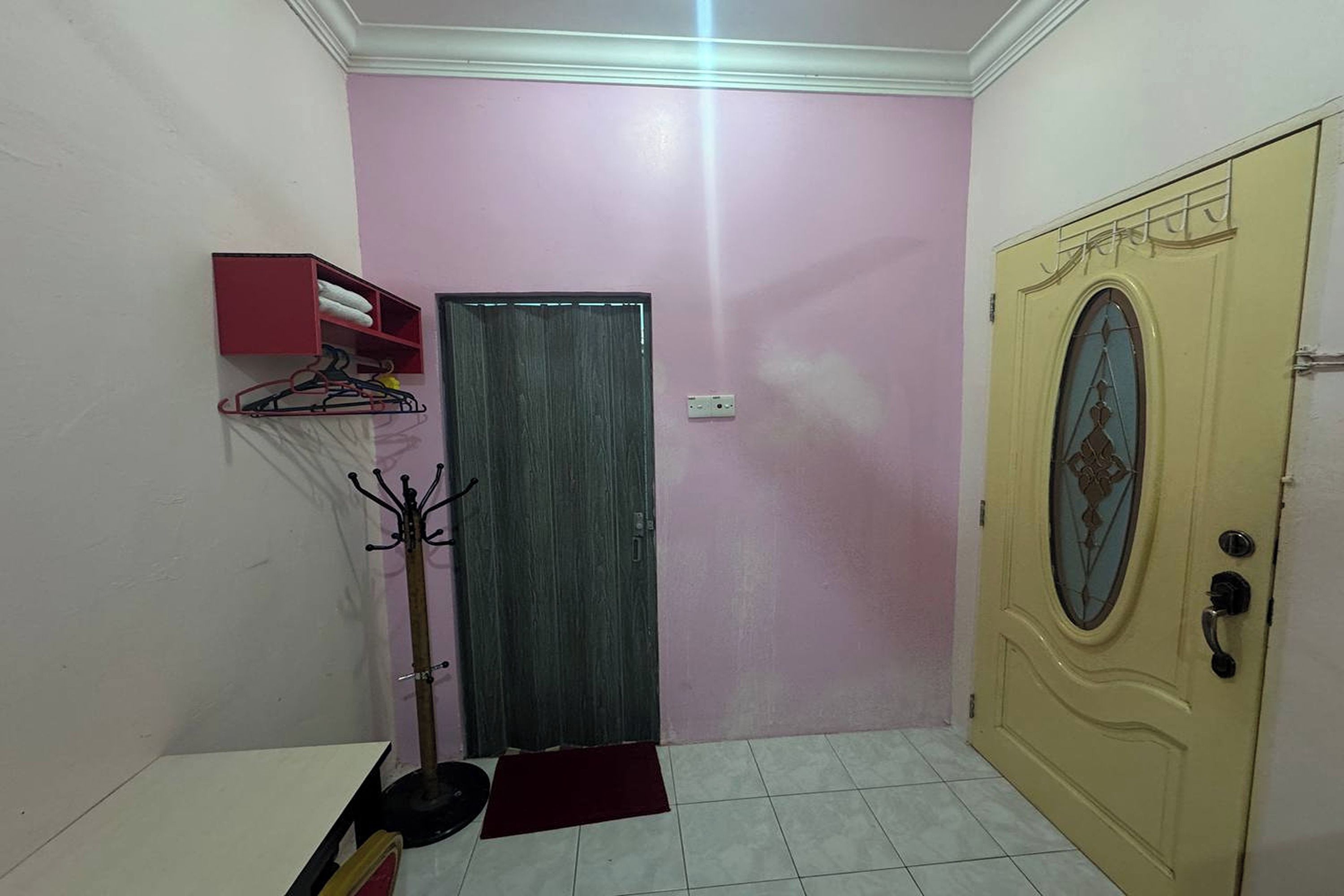 A room with a door, a coat rack, and a shelf with towels.