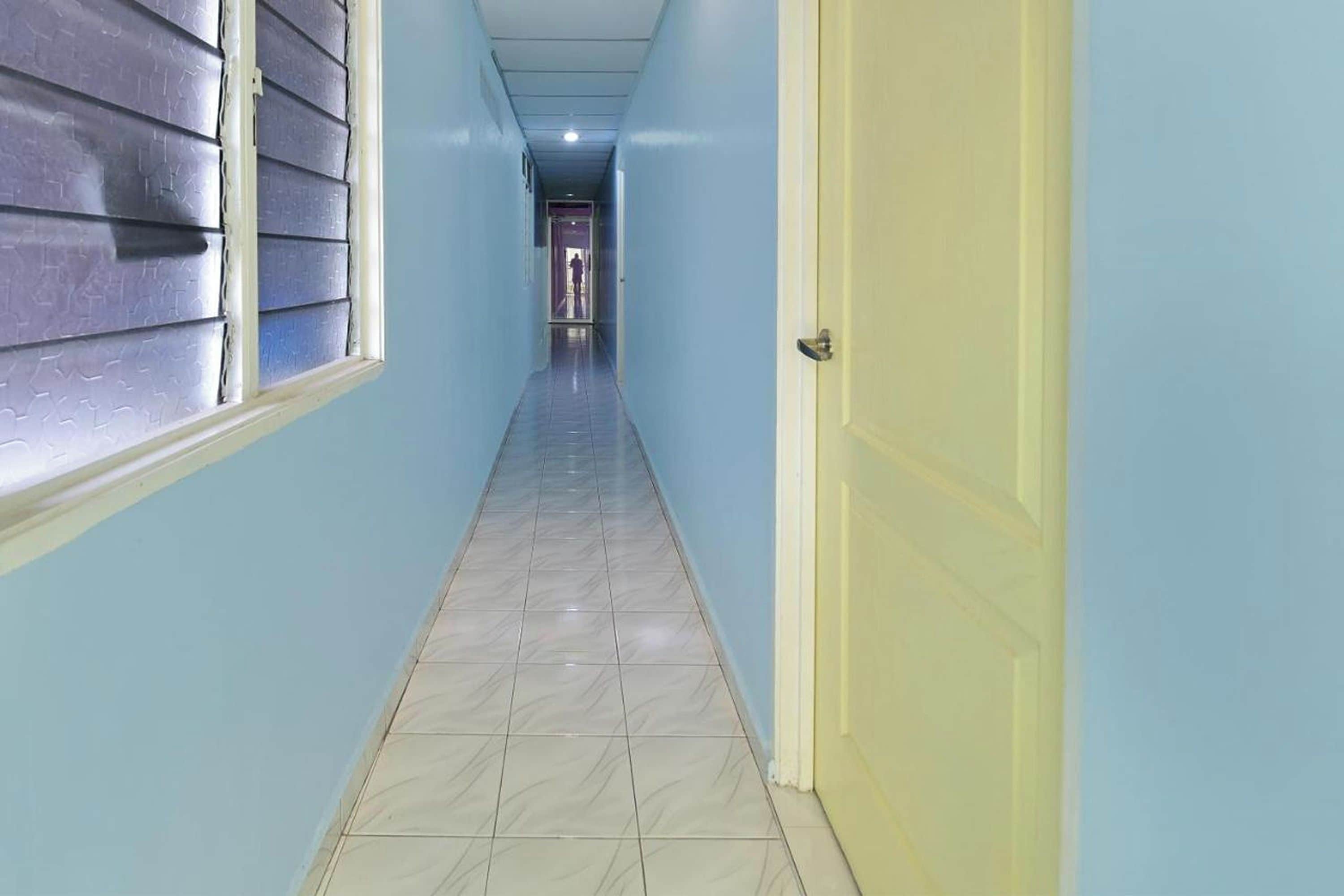 A narrow hallway with a tiled floor, a door on the right, and a window on the left.