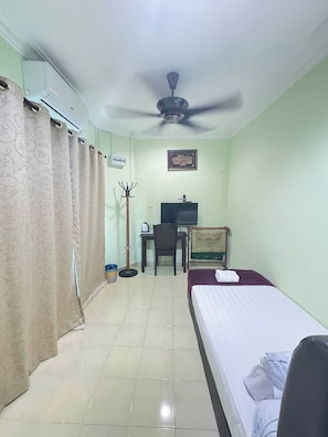 A hotel room with a bed, a desk with a chair, a television, and a ceiling fan. - Darul Salam Orkid INN By Zuzu (Kerteh)
