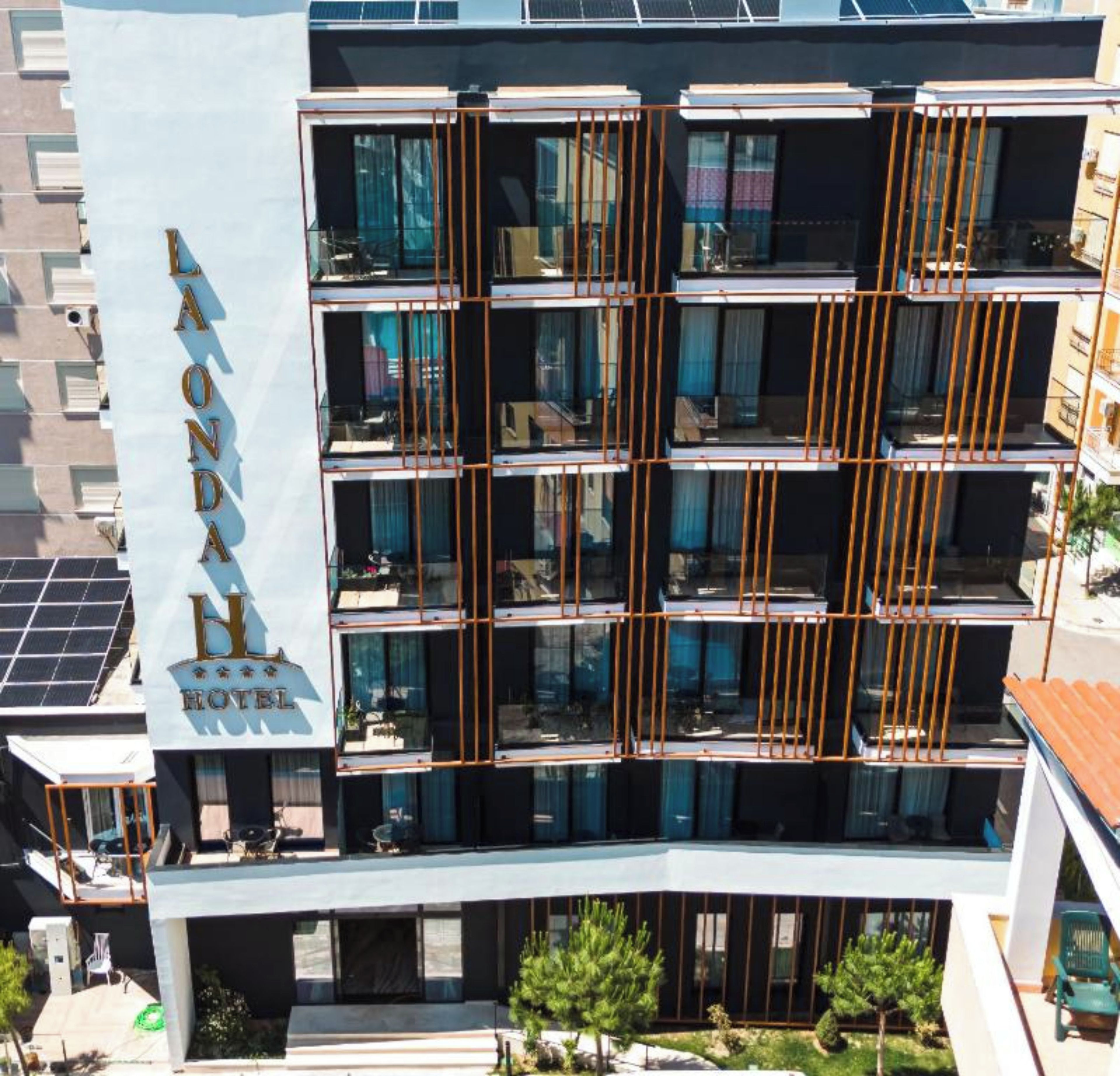 Un hôtel à plusieurs étages, doté de balcons, de grandes fenêtres et d’une enseigne bien visible.