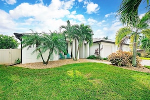 A residential property with a well-maintained lawn, a white fence, and a house with a garage. - A Harbour's Walk |Gulf Access |Pool & Spa |Game Room (Cape Coral)