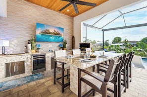 A modern kitchen with a large island, built-in appliances, and a view of a swimming pool. - A Harbour's Walk |Gulf Access |Pool & Spa |Game Room (Cape Coral)