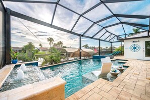 A swimming pool with a water fountain, lounge chairs, and a view of the surrounding area. - A Harbour's Walk |Gulf Access |Pool & Spa |Game Room (Cape Coral)