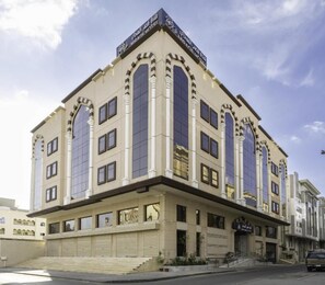 Um hotel com vários andares, uma entrada destacada, grandes janelas e um telhado plano.