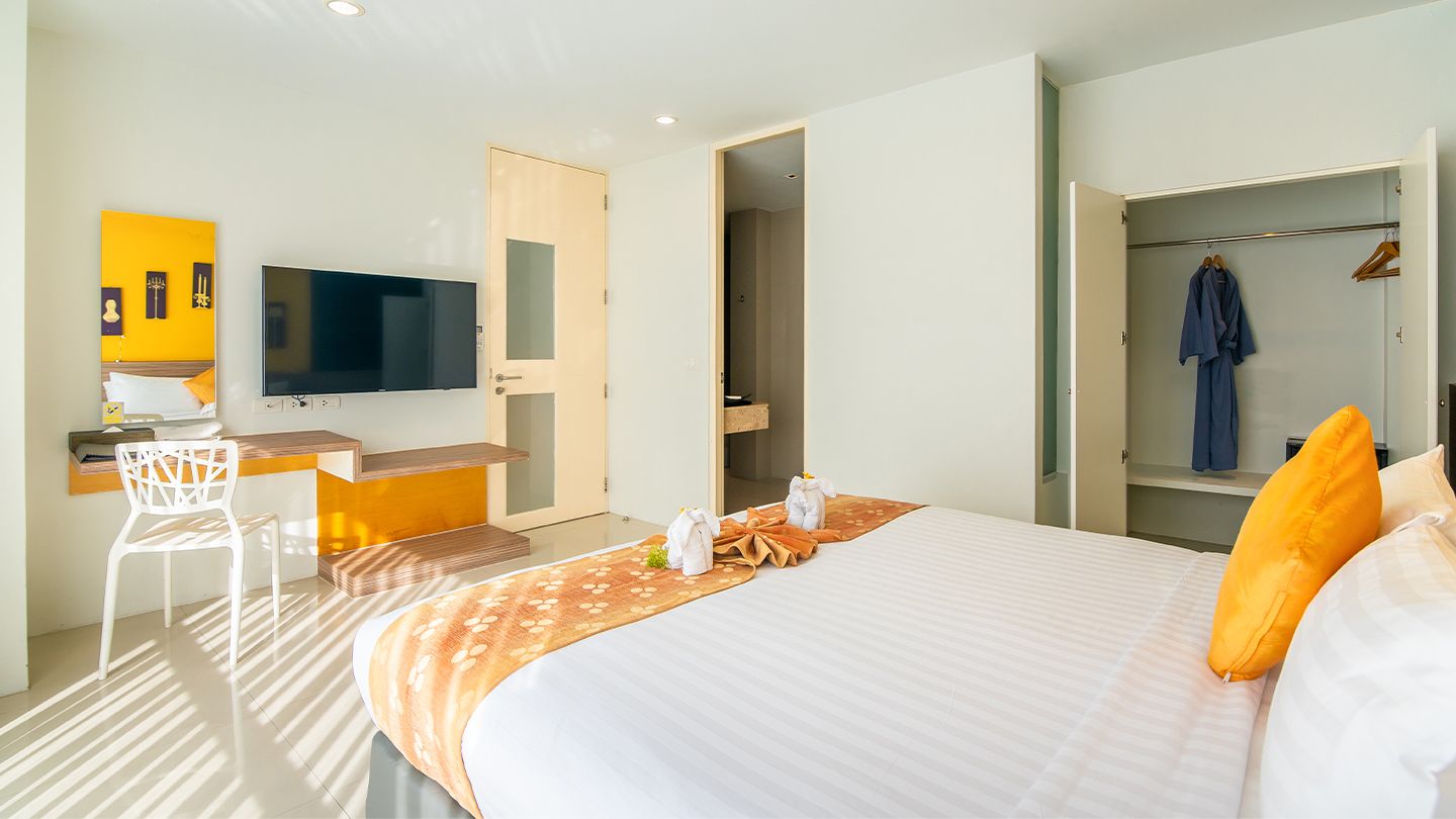 Ein Hotelzimmer mit Bett, Schreibtisch, Fernseher und Kleiderschrank.