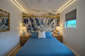 A bedroom with a large bed, two bedside tables, a wall mural, and a window. - Waterfall Cabin - Hot Tub-Cozy Theater & Game Room W/ Surround Sound & Nintendo Switch 2 - Griddle Grill - Outdoor TV area with Swings, Hammocks, & Fire pit! (Denniston)