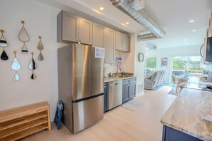 A modern kitchen with stainless steel appliances, a wooden bench, and a large window. - Waterfall Cabin - Hot Tub-Cozy Theater & Game Room W/ Surround Sound & Nintendo Switch 2 - Griddle Grill - Outdoor TV area with Swings, Hammocks, & Fire pit! (Denniston)