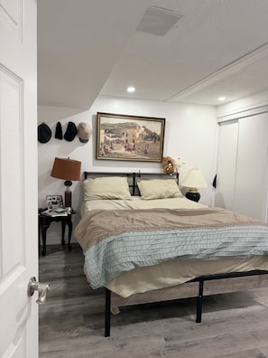Un dormitorio con una cama, un cuadro, una lámpara y un oso de peluche.