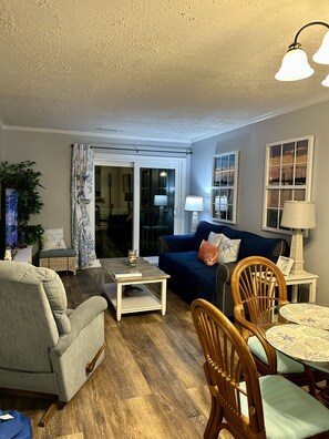 Una sala de estar con sofá, sillones, una mesa de centro y una mesa de comedor con sillas.