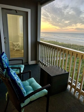 A balcony with a view of the ocean, a door with blinds, and two wicker chairs with cushions. - Chateau By The Sea-Oceanfront-Sleeps4-2b/2b-Laundry-Kitchen-Pool-Free Parking (North Myrtle Beach)