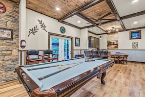 A pool table with chairs, a clock, and a door leading outside. - Mountain View, Pool, Pickleball, Golf & Theater (Sevierville)