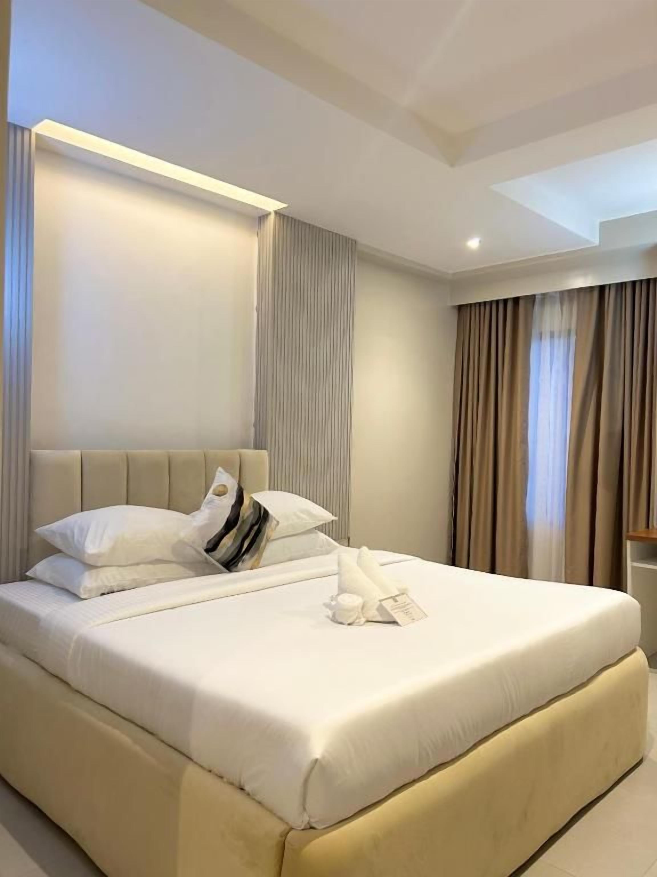 Una habitación de hotel con una cama grande, un cabecero y una mesita de noche.