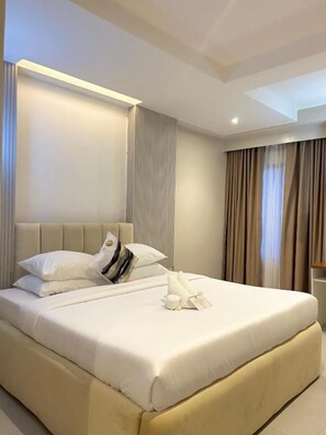 Una habitación de hotel con una cama grande, un cabecero y una mesita de noche.