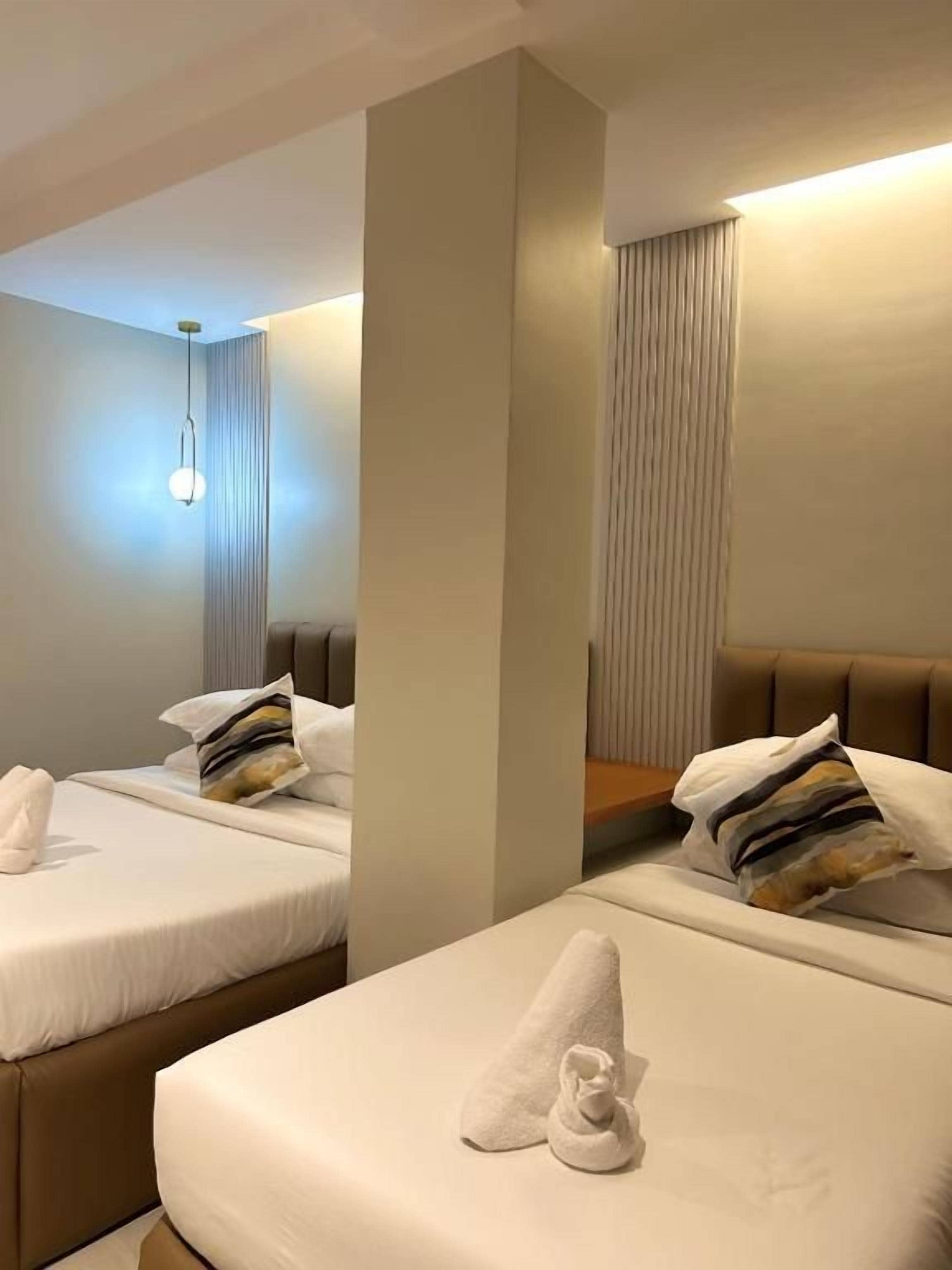 Habitación de hotel con dos camas, cada una con una almohada y una toalla.