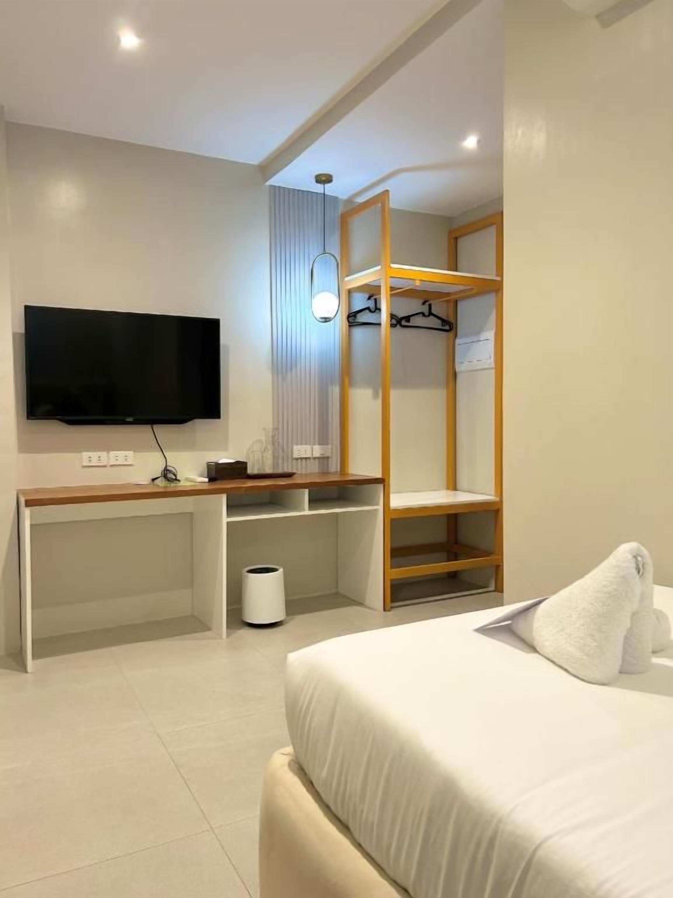 Una habitación de hotel con cama, escritorio, televisor y armario.