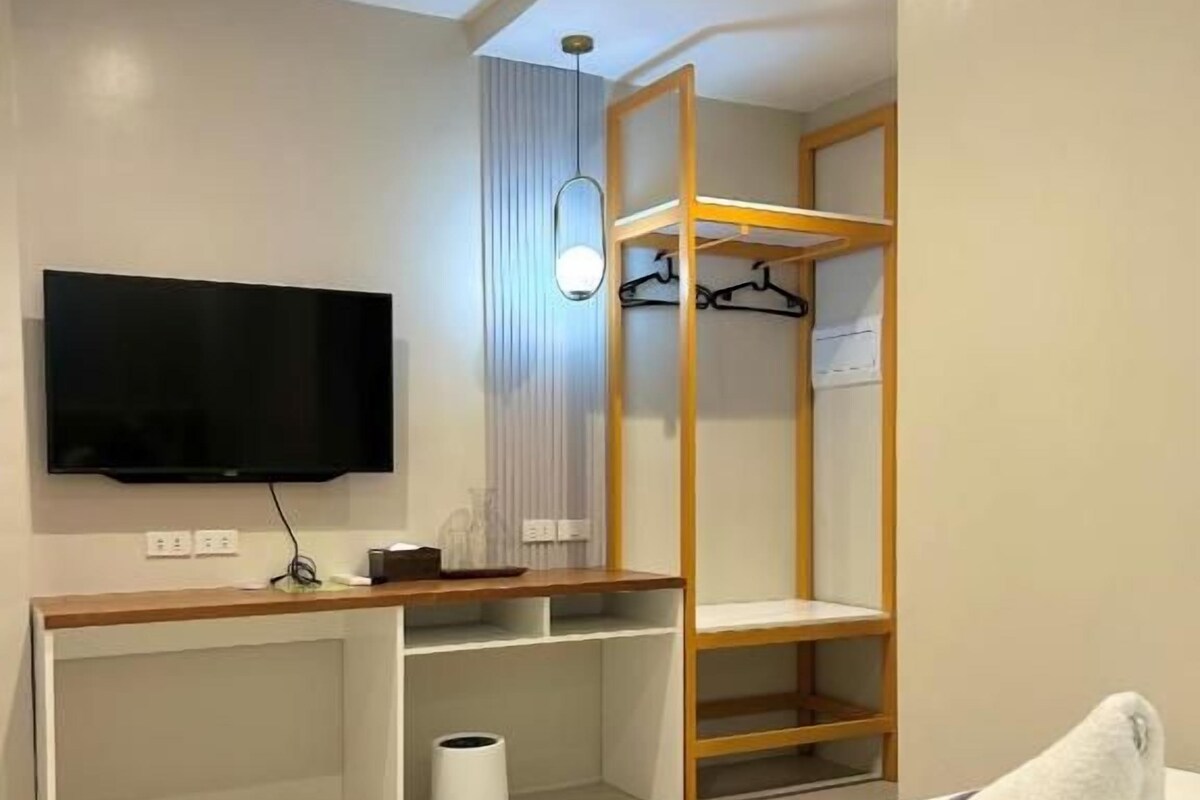 A hotel room with a bed, a desk, a TV, and a wardrobe.