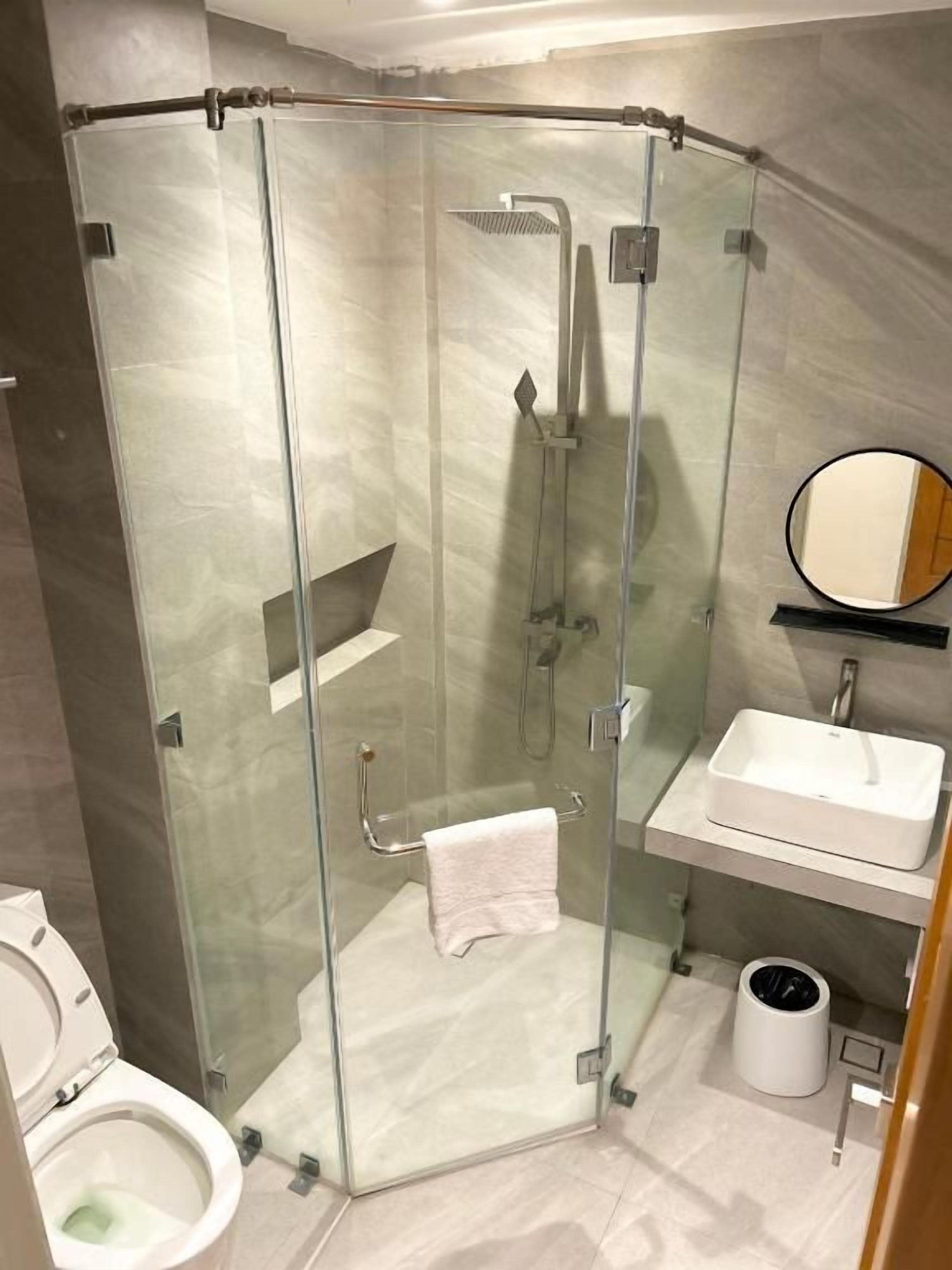 A modern bathroom with a glass-enclosed shower, a white sink, and a toilet.