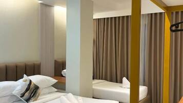 A hotel room with a bed, a sofa, a small table, and a curtain.