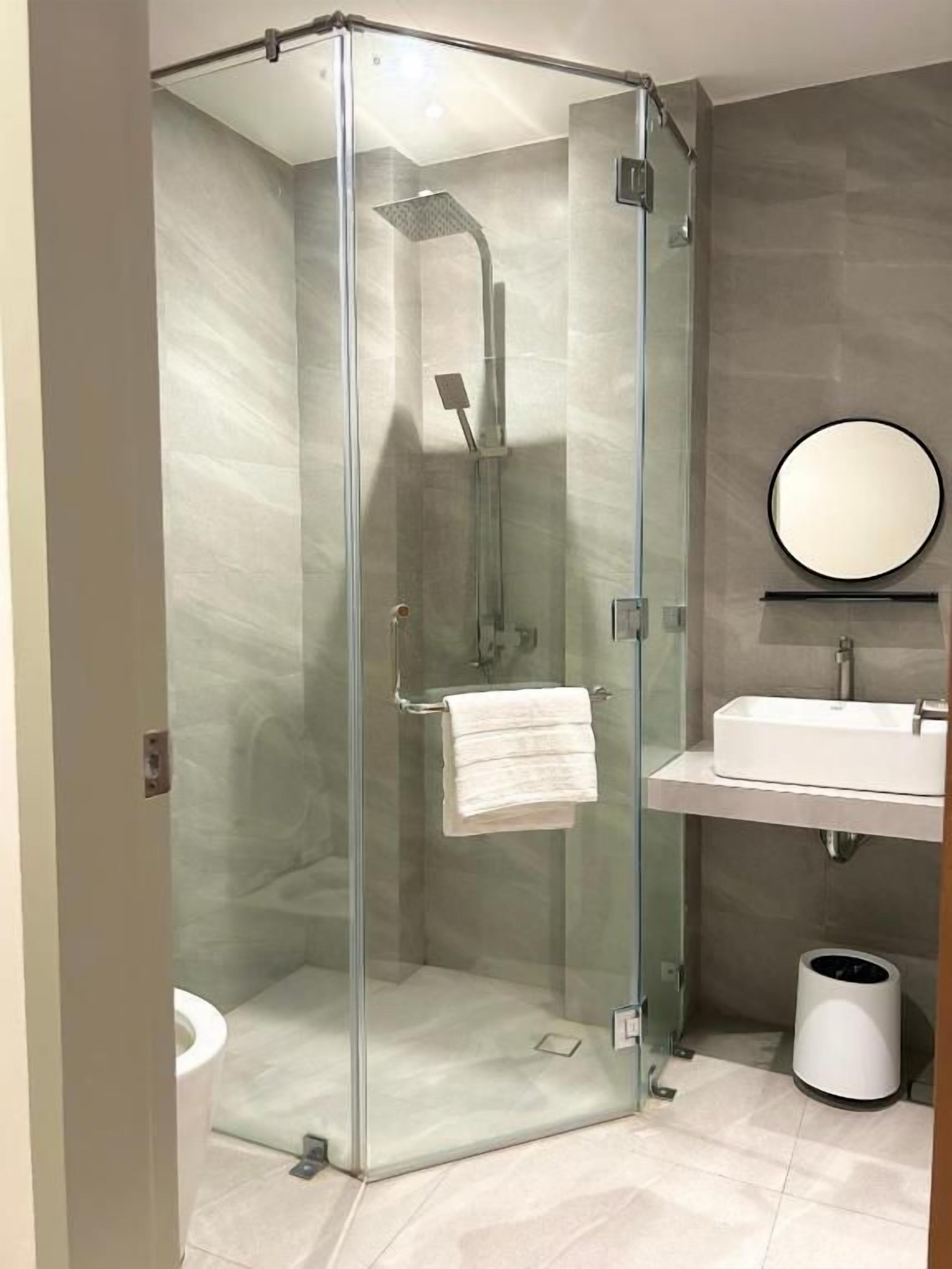 A modern bathroom with a glass-enclosed shower, a sink, and a mirror.