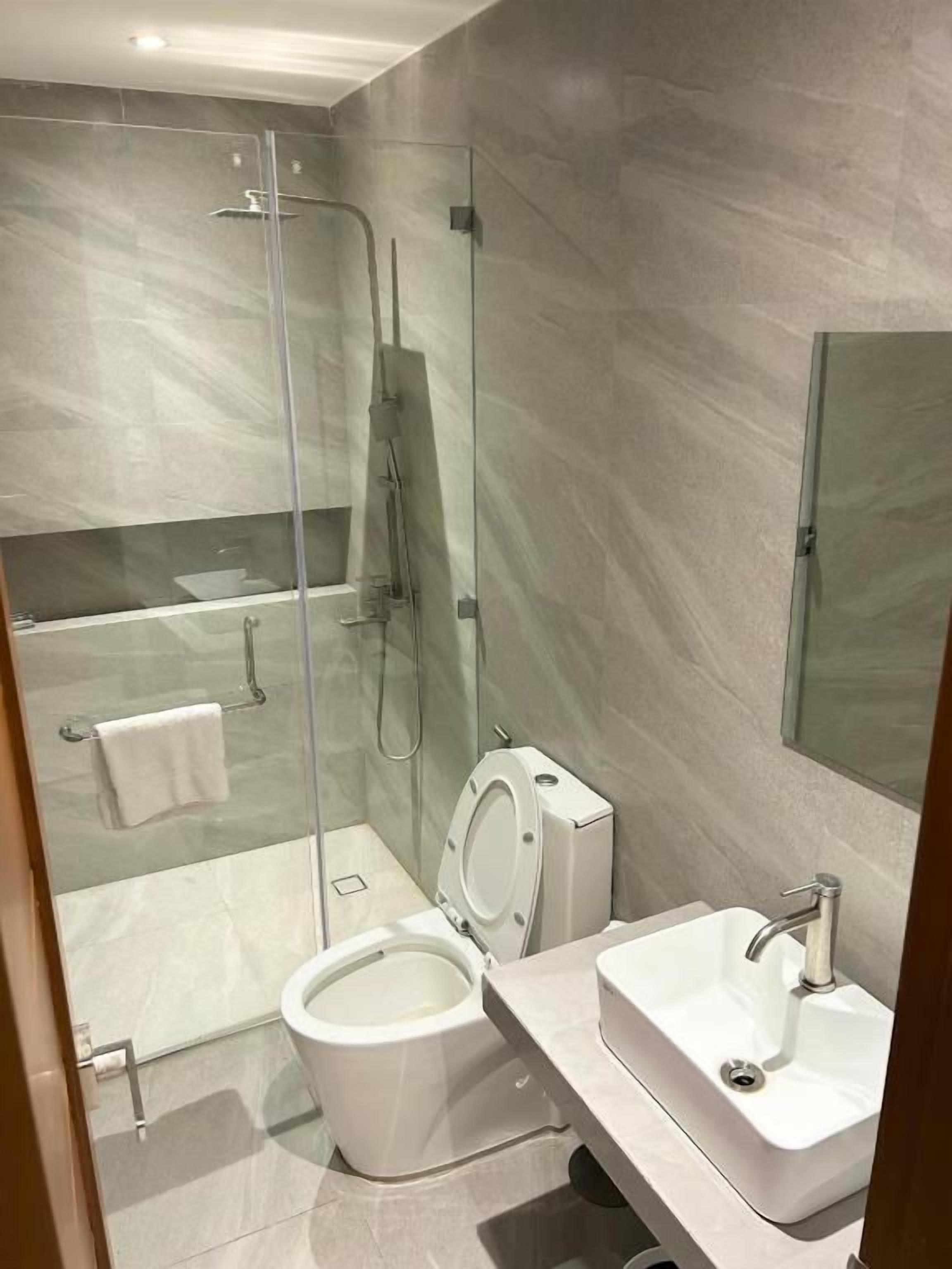 A modern bathroom with a glass-enclosed shower, a toilet, and a sink.